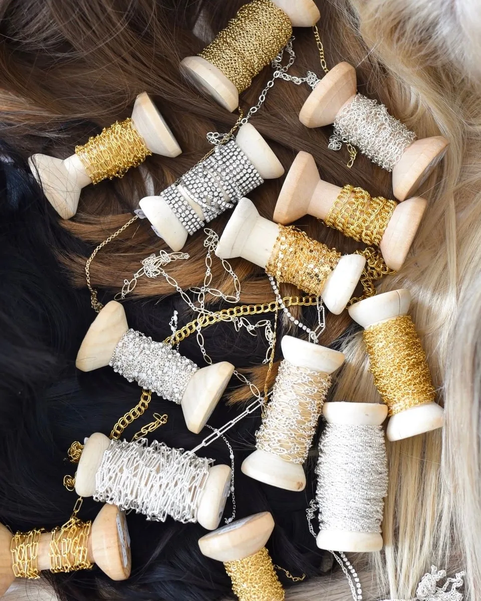 Gold and silver jewelry chain wound around small wooden spools