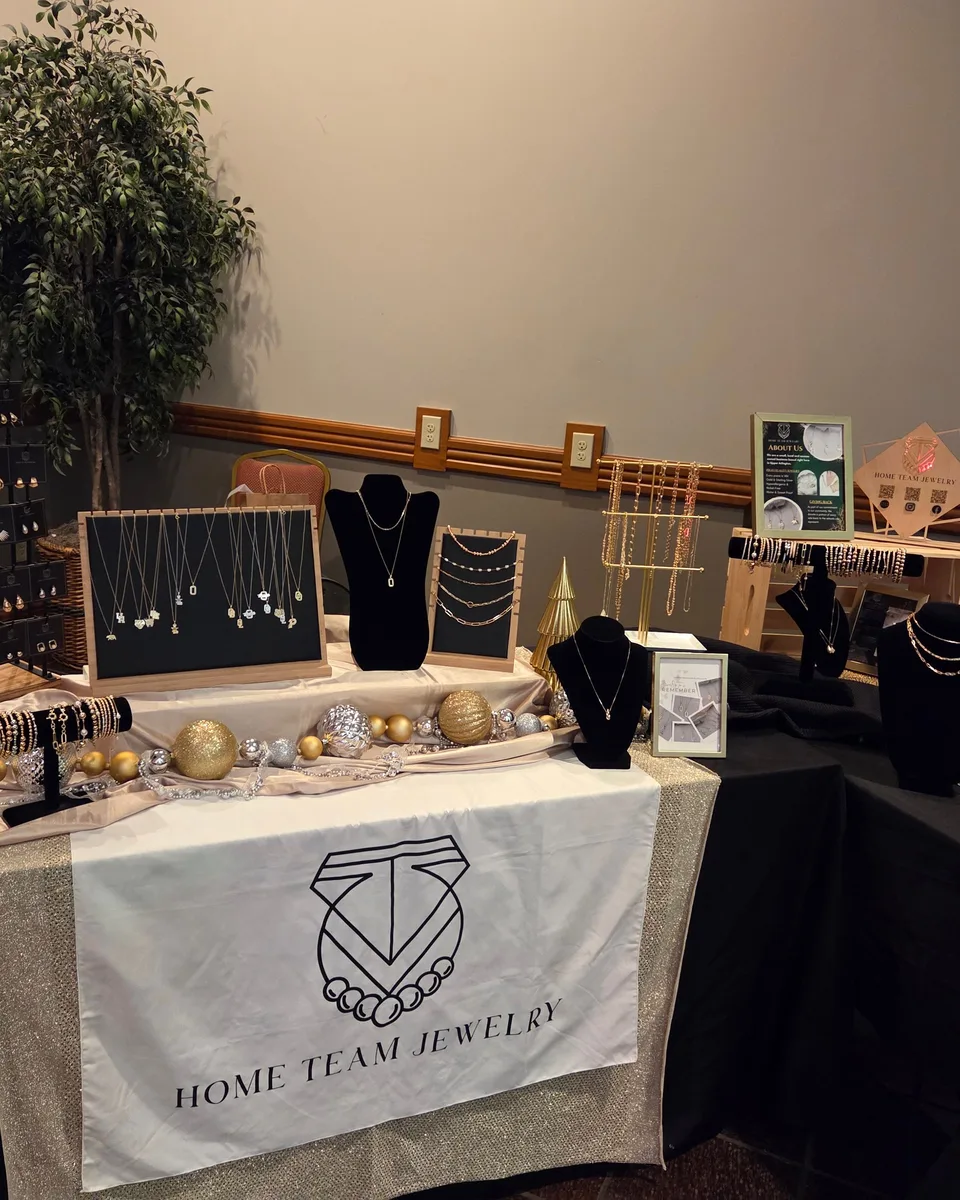 A holiday market booth displaying gold and silver jewelry on black stands