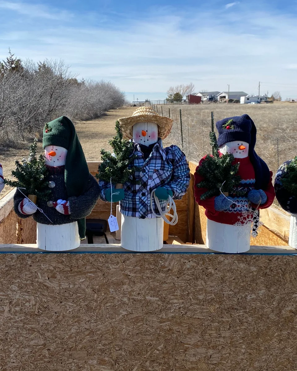 Five handcrafted wooden snowmen dressed in recycled sweaters and hats