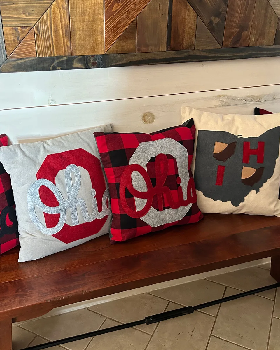 A row of red, gray and buffalo-plaid Ohio appliqué pillows