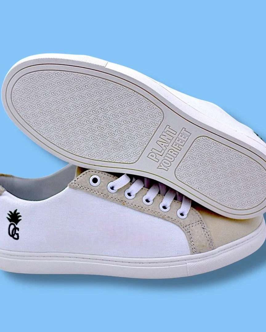 A pair of white plant-based sneakers displayed against a light blue background