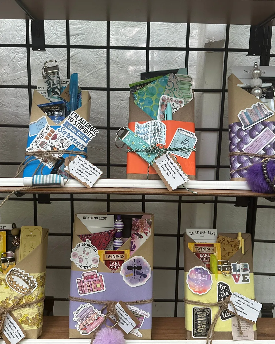 Wrapped books and colorful book-themed gifts arranged on black wire shelves