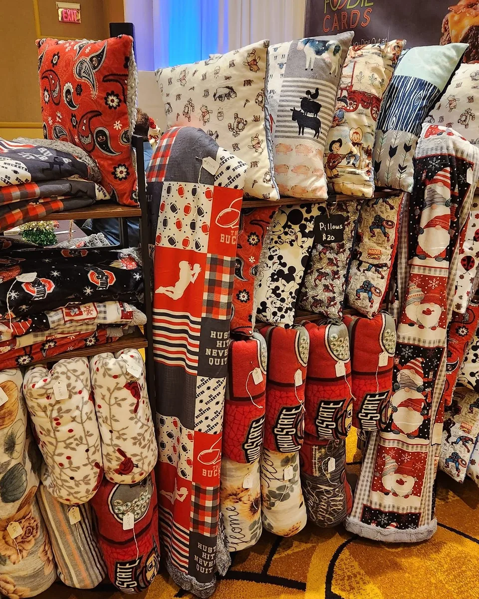 Rows of colorful handmade blankets and pillows displayed at a market booth