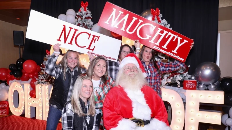 A group poses with Santa and the Nice and Naughty signs.