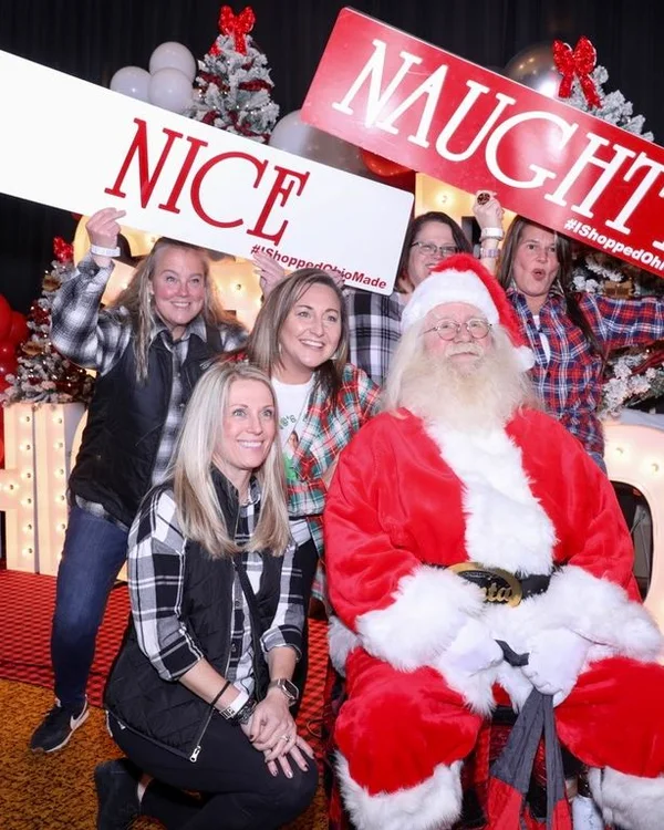 A group poses with Santa and the Nice and Naughty signs.