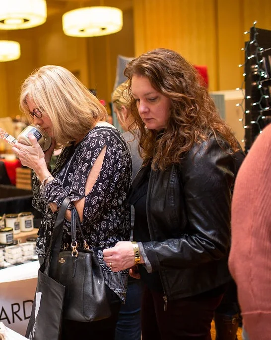 Two shoppers look over handmade candles at a booth at the 2018 Ohio Made Holiday Market.