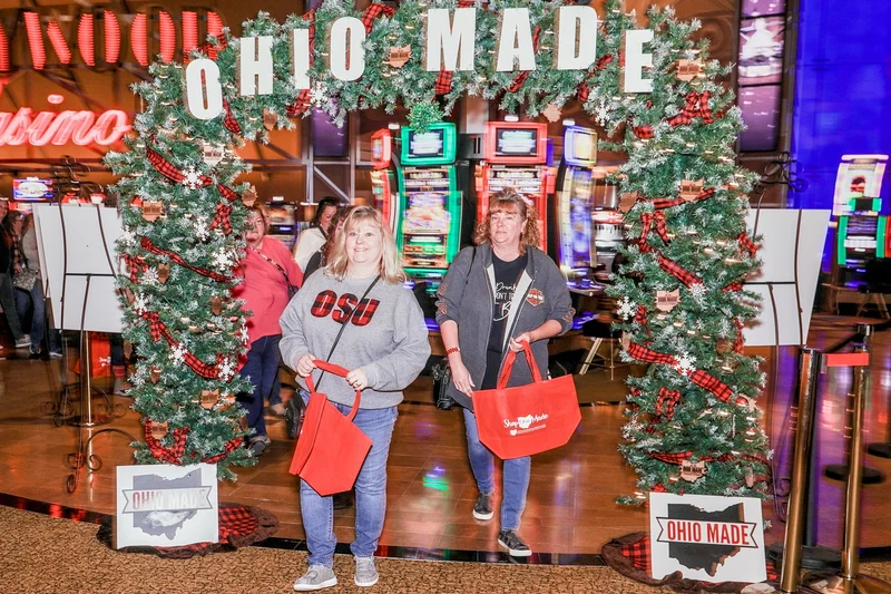 Two guests with red Shop Ohio Made totes walk out under the garland Ohio Made arch at the 2022 Ohio Made Holiday Market.