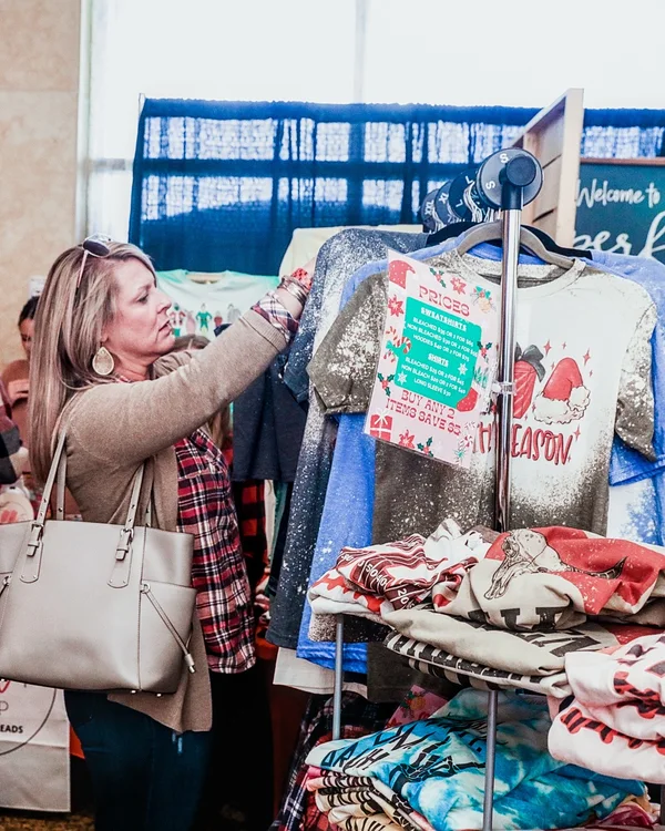 A shopper looks through a rack of holiday shirts at the 2022 Ohio Made Holiday Market.