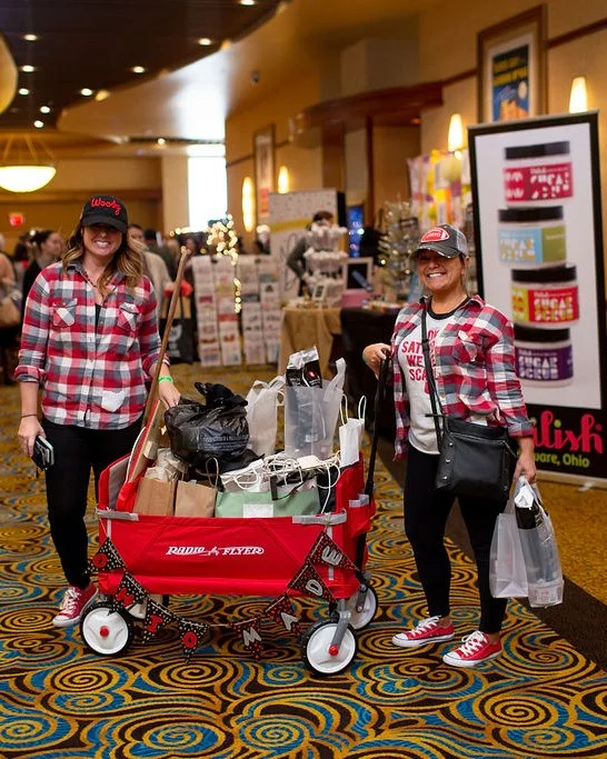 Two shoppers in plaid pose with a wagon at the 2018 Ohio Made Holiday Market.