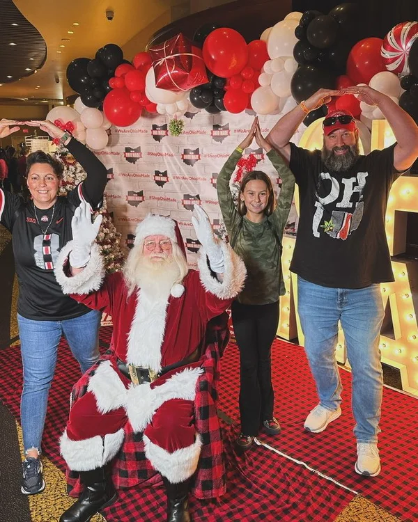 Shoppers make the letters O-H-I-O with their arms beside Santa.