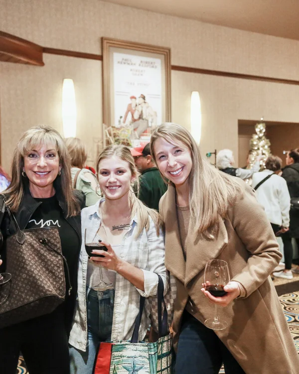 Three friends with wine glasses and tote bags pose together at the 2019 Ohio Made Holiday Market.