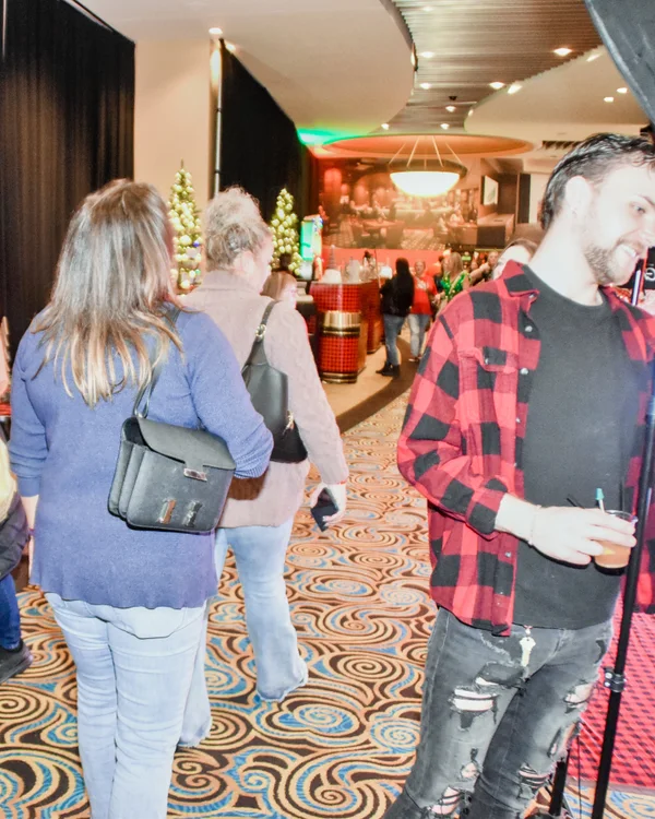 Shoppers stroll down a carpeted aisle past booths at the 2025 Ohio Made Holiday Market.