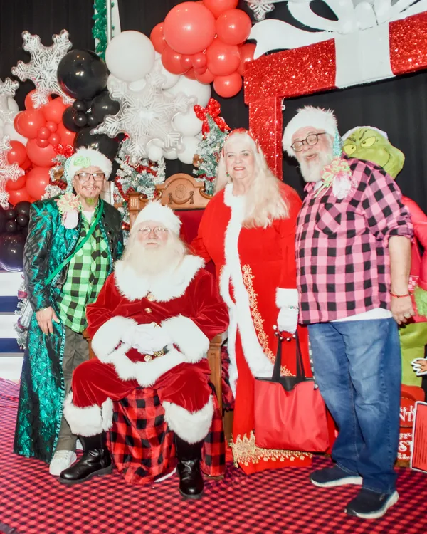 Santa sits beside Mrs. Claus, a costumed guest and a guest in plaid in front of giant lit Ohio Made letters.