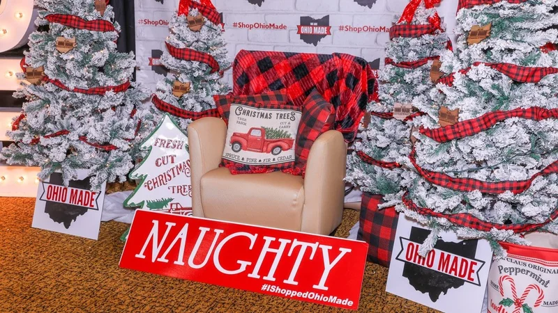 A plaid cushion chair between flocked trees with a Naughty sign.