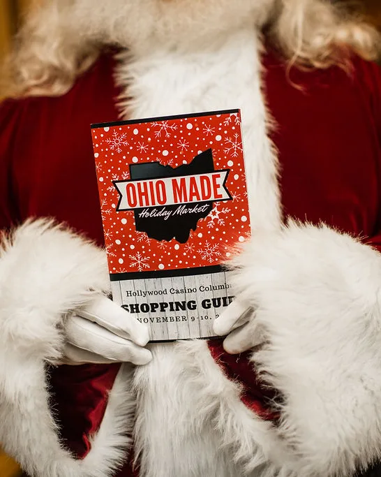Santa holds a printed shopping guide against his coat.