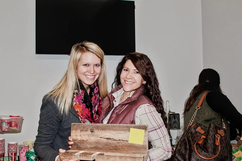 Two smiling guests hold a handmade wooden sign at the 2016 Ohio Made Holiday Market.
