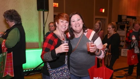 Two friends in plaid hold drinks at the market.