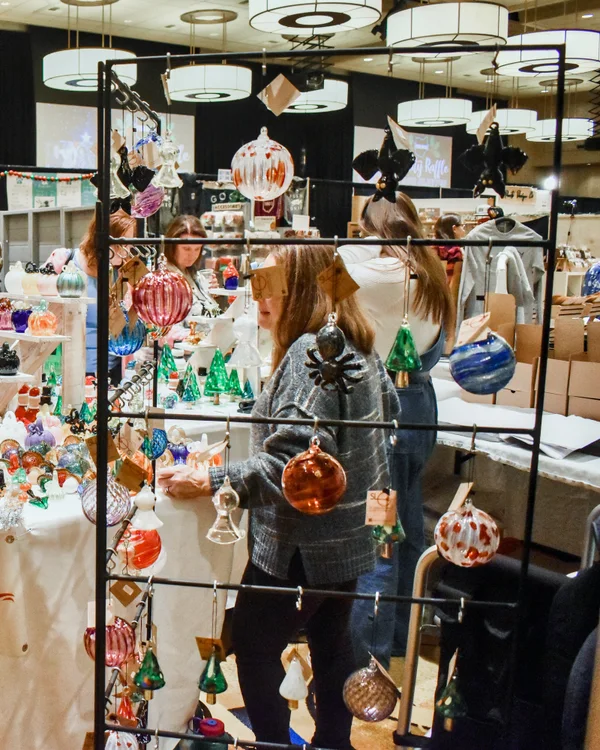 A shopper picks out a glass ornament from a hanging display at the 2023 Ohio Made Holiday Market.