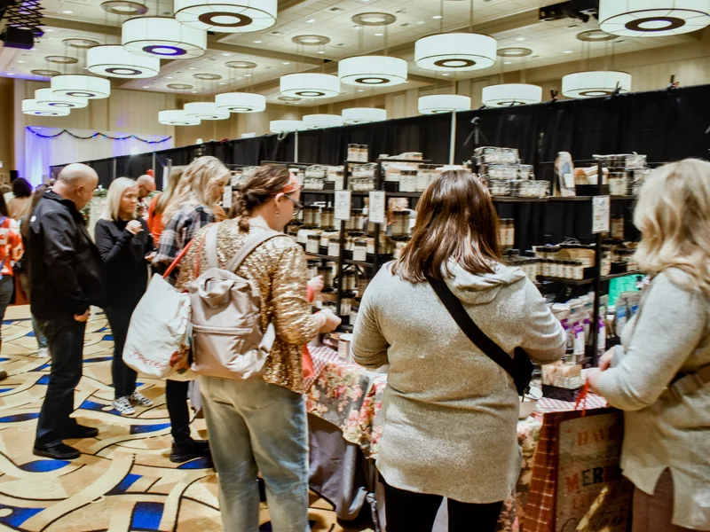 Shoppers stand at a table under the chandeliers at the 2023 Ohio Made Holiday Market.