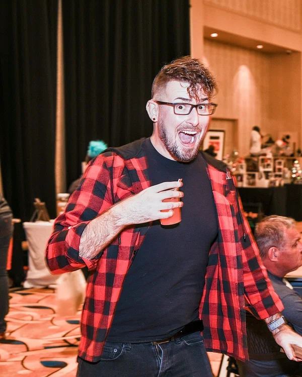 A shopper in a red plaid shirt laughs with a drink in hand at the 2022 Ohio Made Holiday Market.