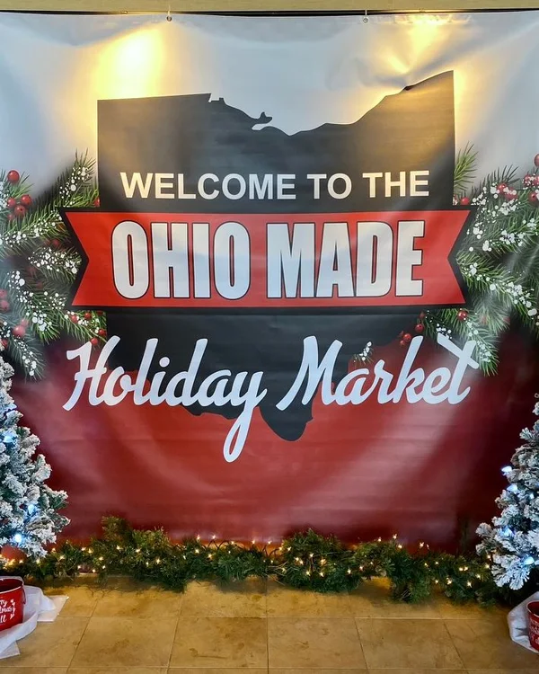 A Welcome to the Ohio Made Holiday Market banner between two flocked trees.