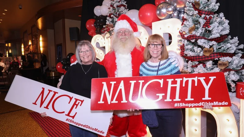 Two shoppers hold Nice and Naughty signs beside Santa.