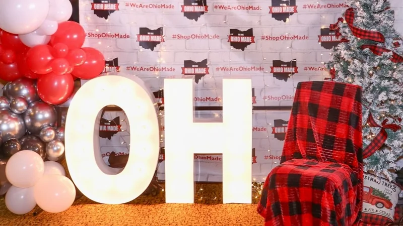 Lit OH letters, a plaid chair and flocked trees in front of a balloon photo wall.