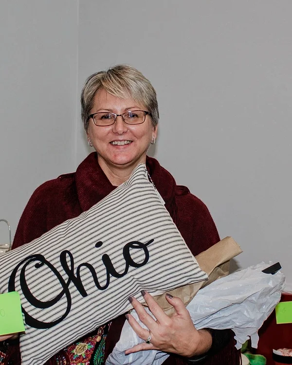 A smiling shopper holds an Ohio pillow at the 2016 Ohio Made Holiday Market.