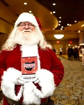 Santa holds a Shopping Guide in the market hallway.