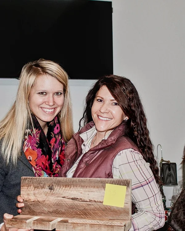 Two smiling guests hold a handmade wooden sign at the 2016 Ohio Made Holiday Market.